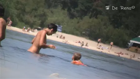 Pisando detrás de personalidades desnudas en una gran playa nudista